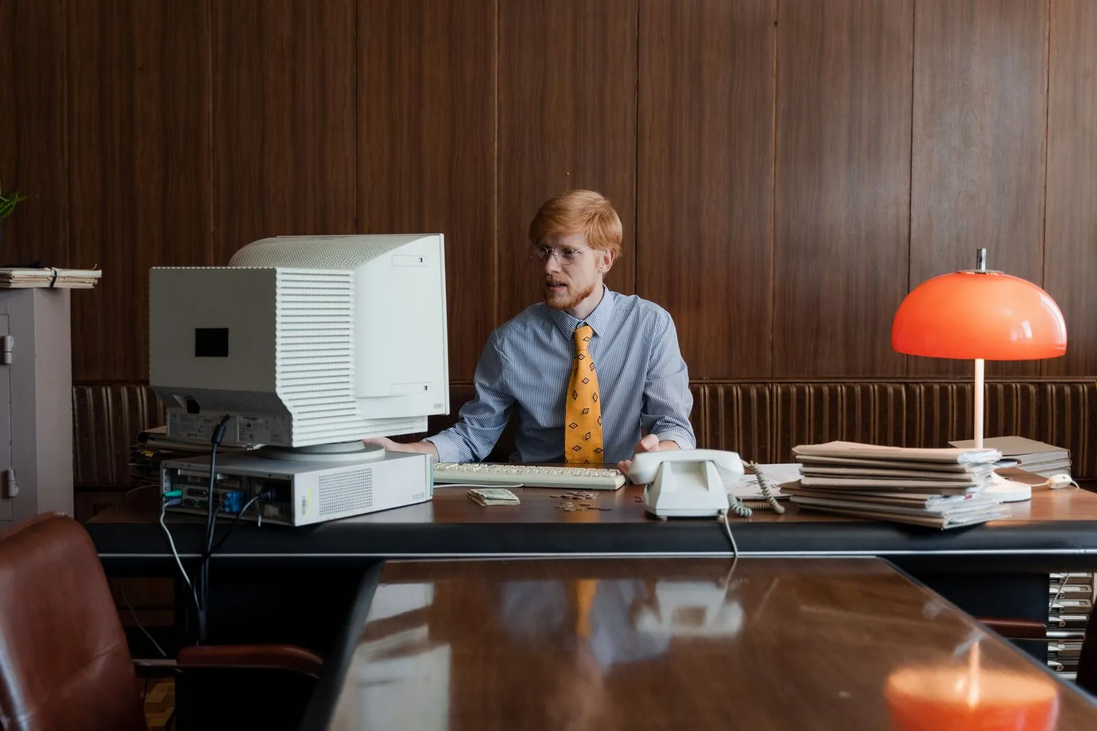 Retro office setup with a businessman working at a computer, surrounded by vintage decor.